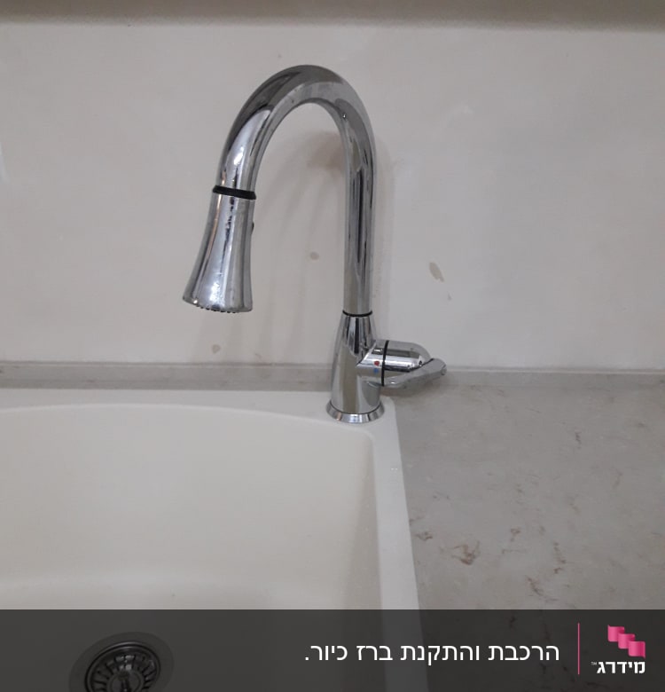 ברז נירוסטה מעל כיור לבן במטבח